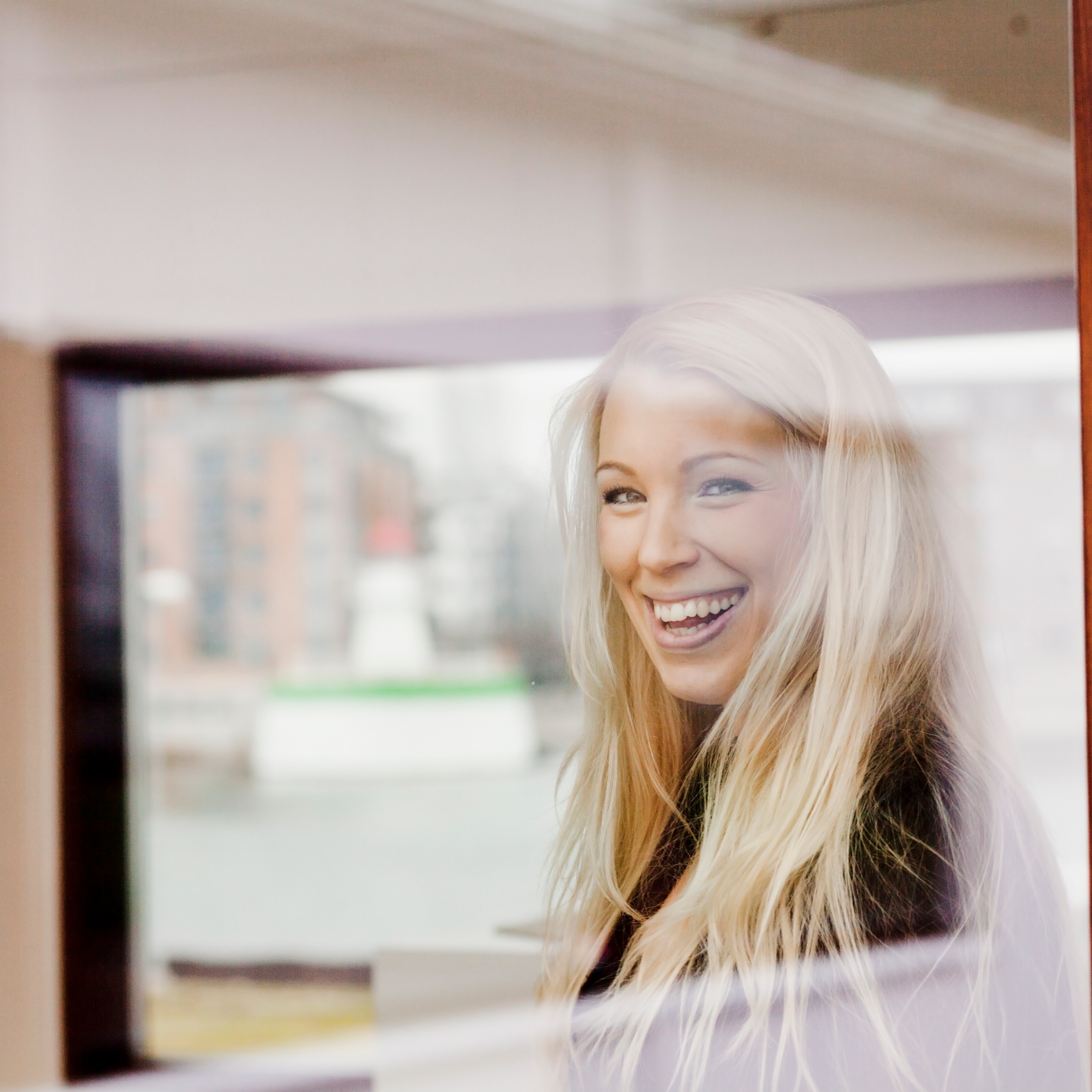 Kvinde smiler ud af vinduet forbi hun er glad for at bruge Microsoft 365 intranet