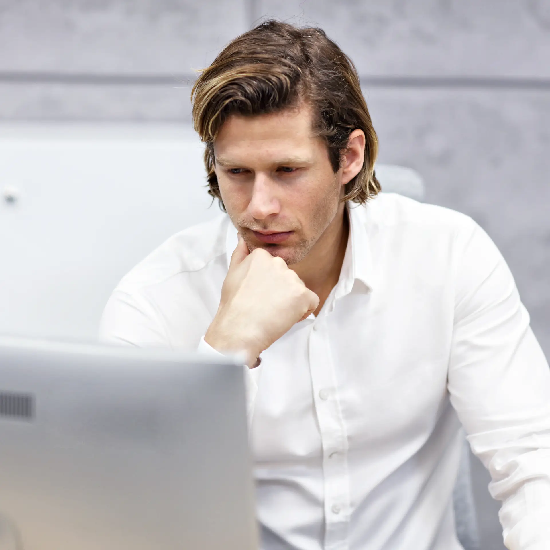 Mand i hvid skjorte kigger på SharePoint på sin computer