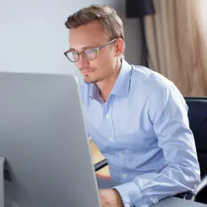 Mand på et kontor sidder og arbejder med sagshåndtering i SharePoint på sin computer