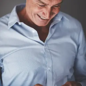 En mand smiler ned i hans telefon da han er i gang med en integration af workflows i SharePoint og det fungere godt for ham