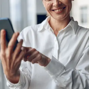 Kvinde er glad fordi hun bruger en kvalitetshåndbog i SharePoint på telefon