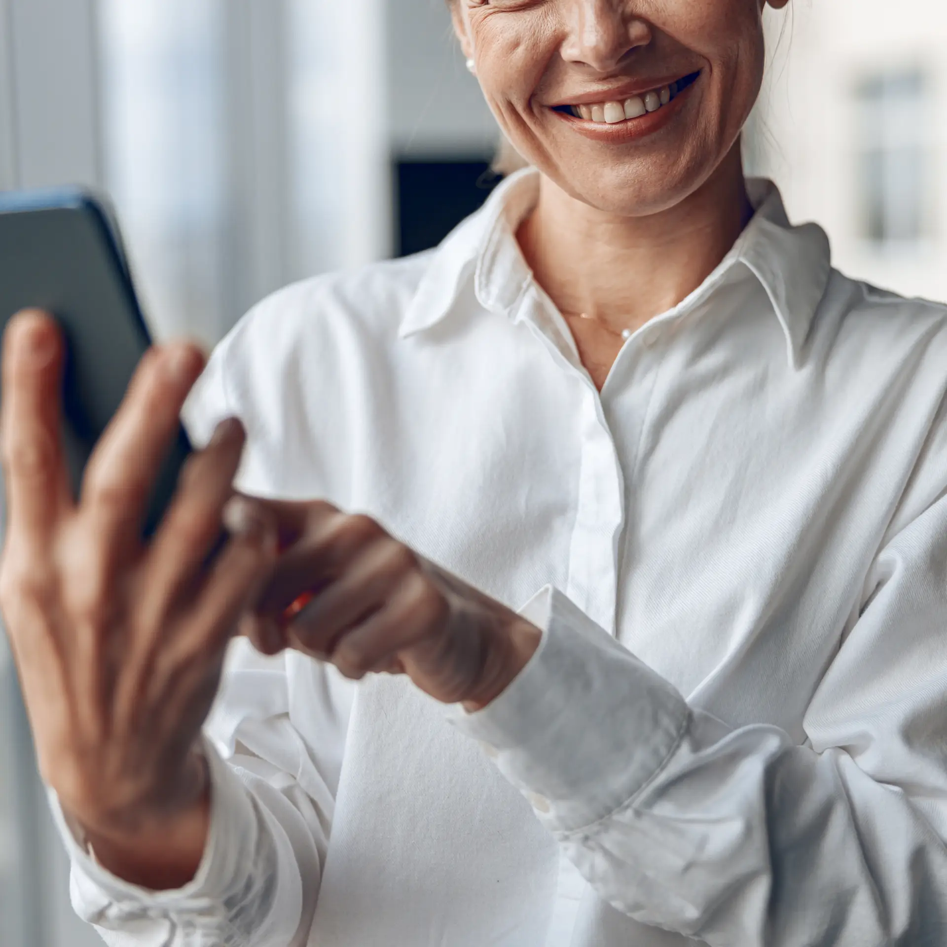 Kvinde er glad fordi hun bruger en kvalitetshåndbog i SharePoint på telefon