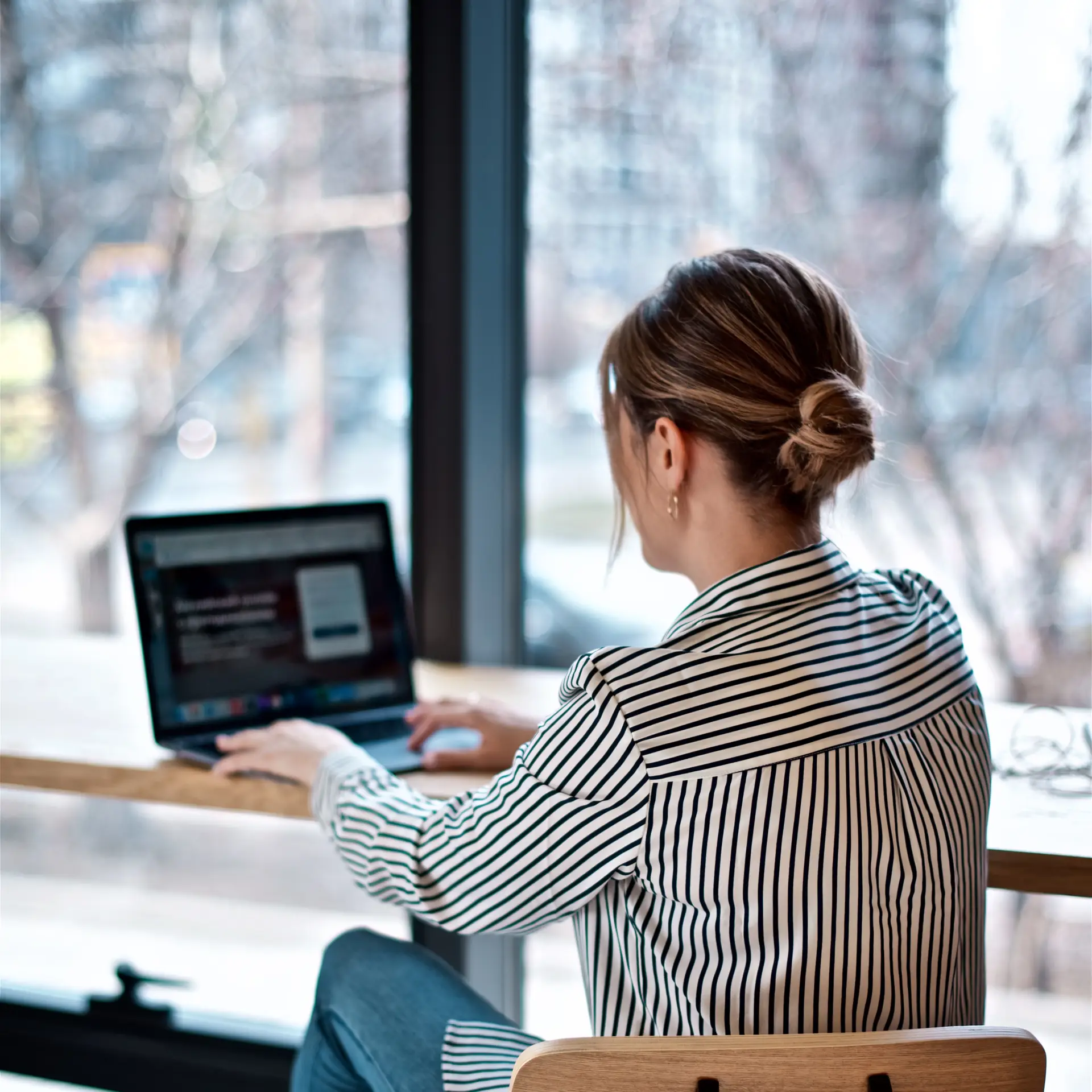 En kvinde ved et bord ud et stort vidue og tjekker sin online kvalitetshåndbog på SharePoint, som Blue Dock har hjulpet med at udarbejde