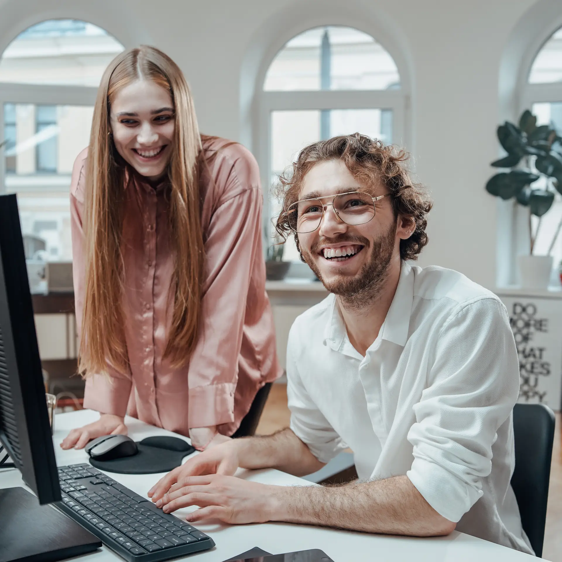To personer sidder på et kontor og smiler efter de har fået hjælp af Blue Dock til at migrerer til SharePoint Online