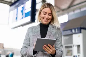 Projektleder i lufthavn er smiler og er fordi hun kigger på sin Microsoft Copilot Agent på sin tablet, som hjælper hende med systematisk opgaver, så hun bedre har tid til sine kunder