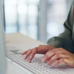 Medarbejder skriver på et tastatur og søger sin i medarbejderhåndbog i SharePoint fra Blue Dock